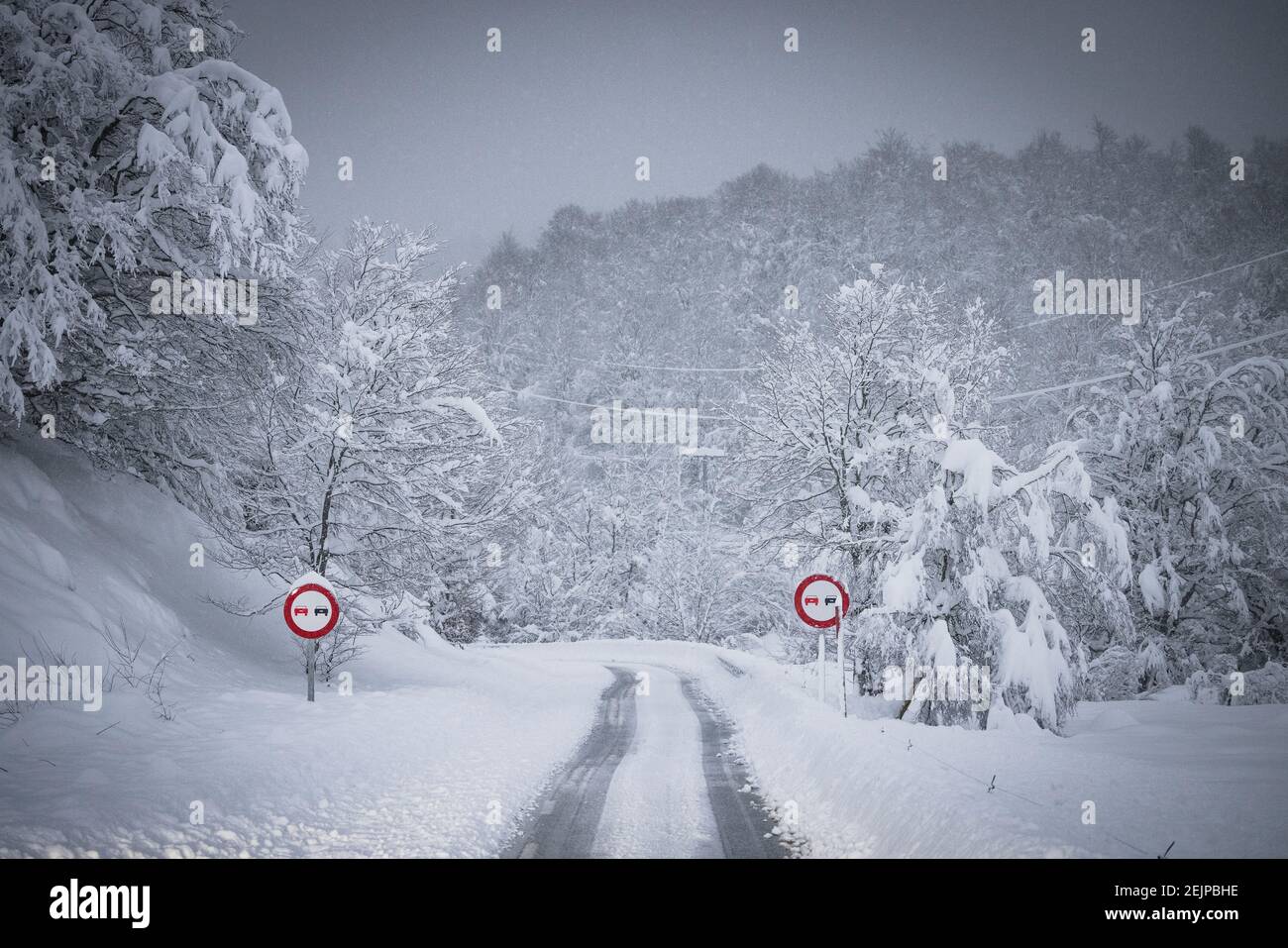 high mountain road and traffic signs in the middle of a snowfall Stock Photo