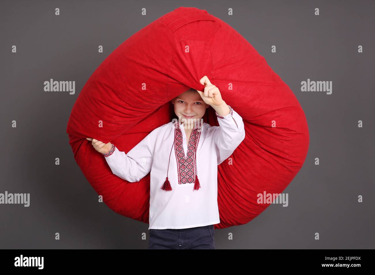 Little boy hold up big red bean bag chair with wily smile Stock Photo