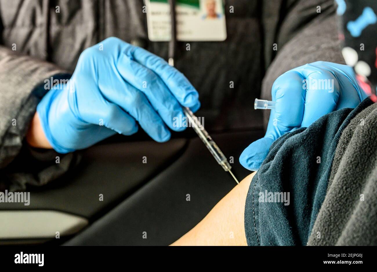 A nurse injecting the covid-19 vaccination into a woman's arm at a drive-thru distribution facility. Stock Photo
