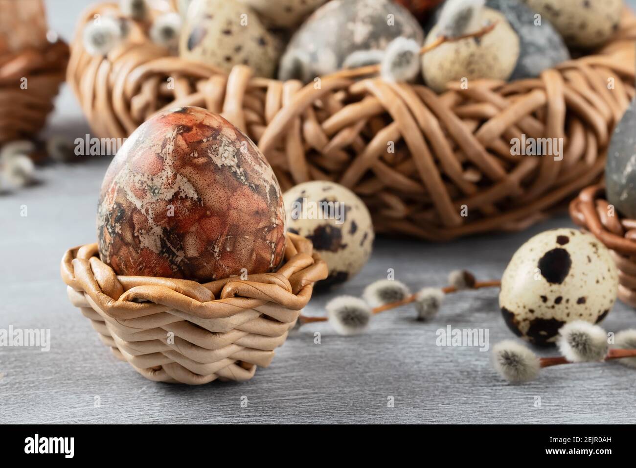 Easter composition - several marble eggs painted with natural dyes in a wicker nest and baskets. Stock Photo