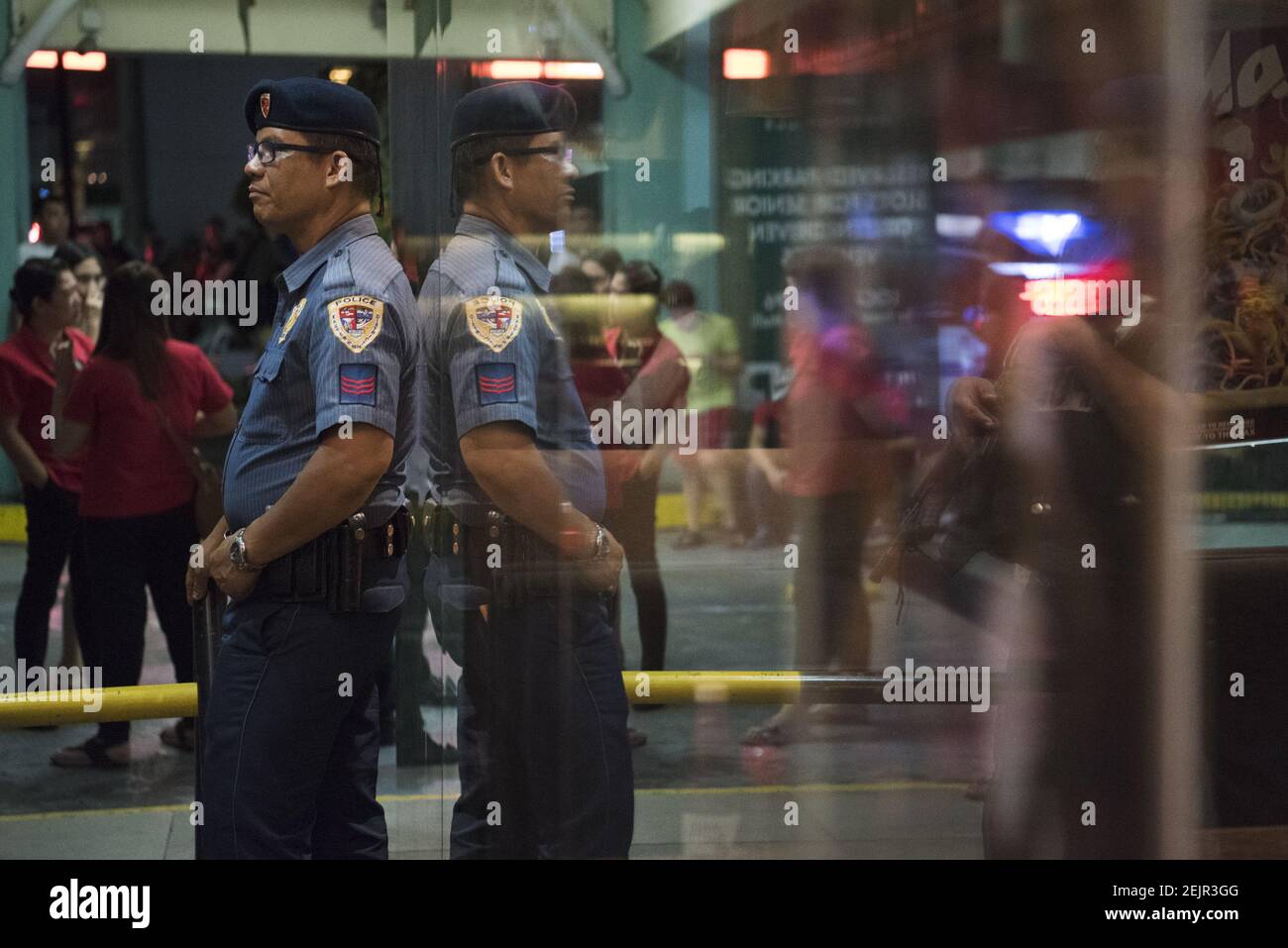 A police officer stands on guard outside V shopping Mall in Manila ...