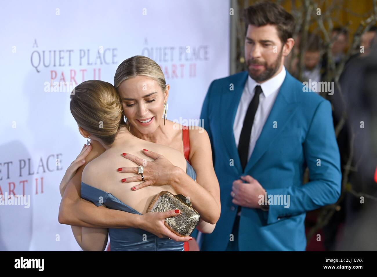 Emily Blunt (red dress), with John Krasinski (blue suit) hugs actress(02)