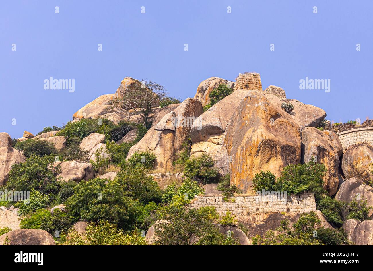 Chitradurga, Karnataka, India - November 10, 2013: Fort or Elusuttina Kote. Brown stone rampart wall cuts through boulder hill under blue sky with som Stock Photo