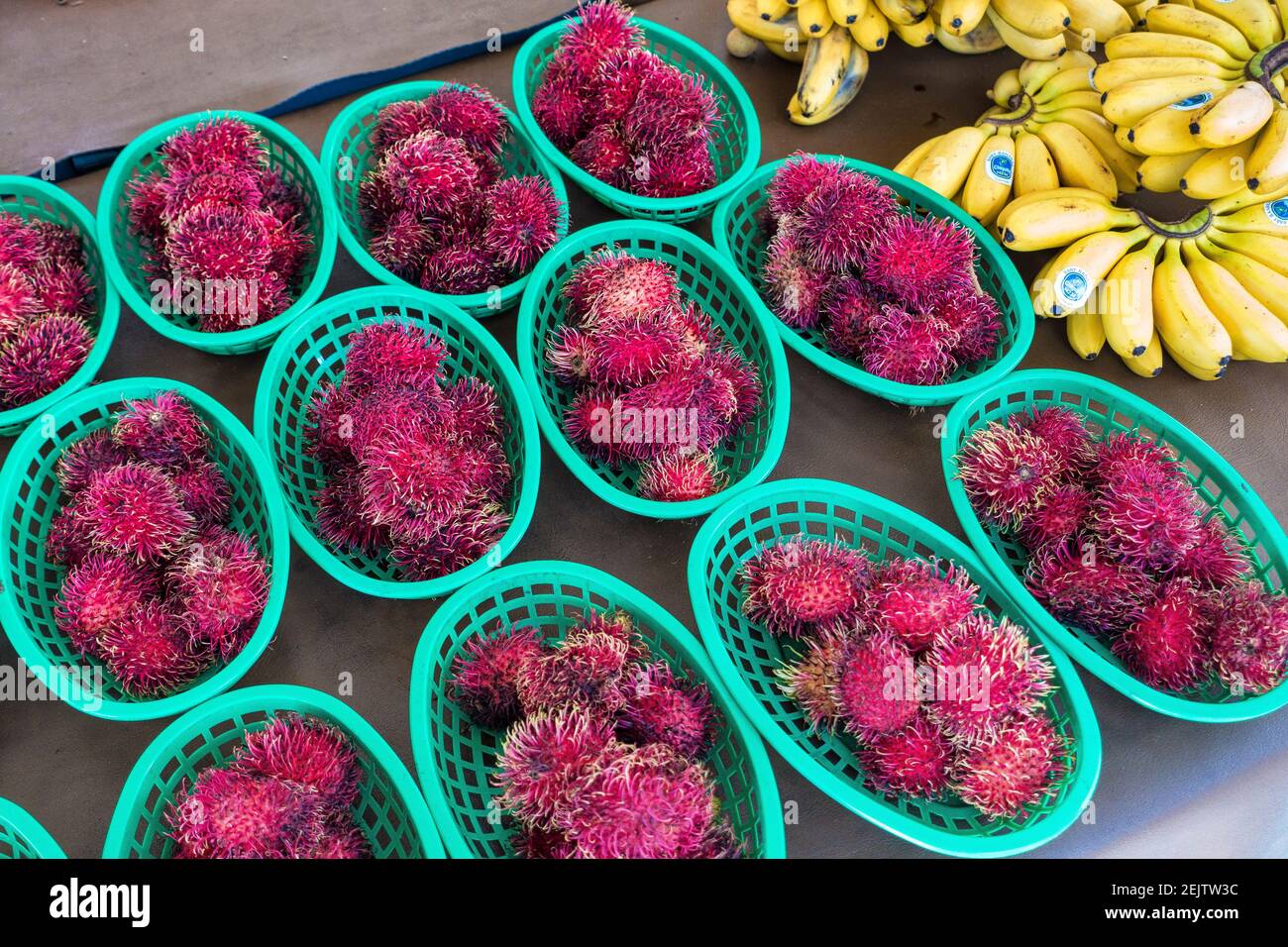 Baskets of tropical rambutan fruit for sale at an outdoor market on the