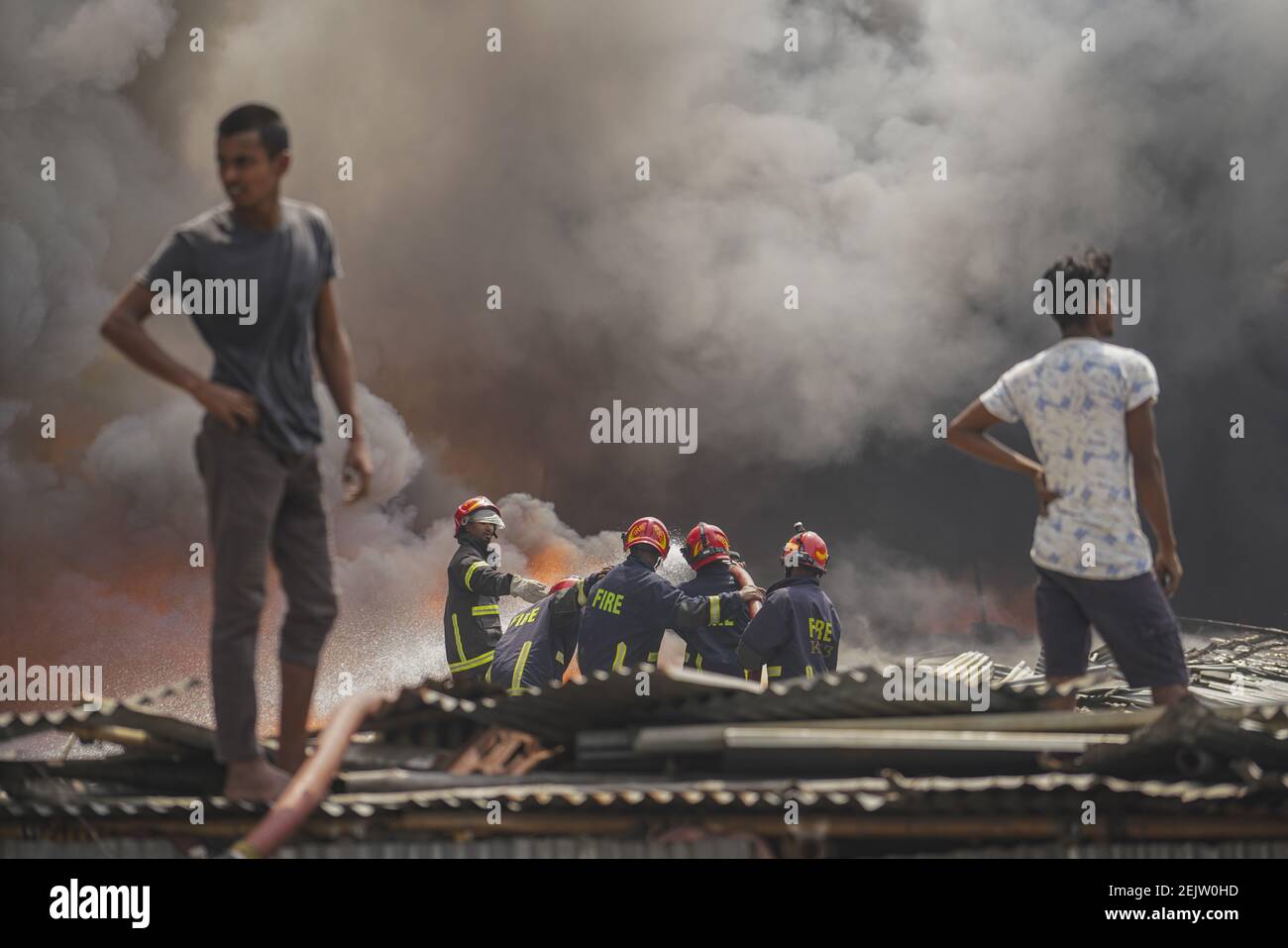 Firefighters and local people work to extinguish a fire at a slum area ...