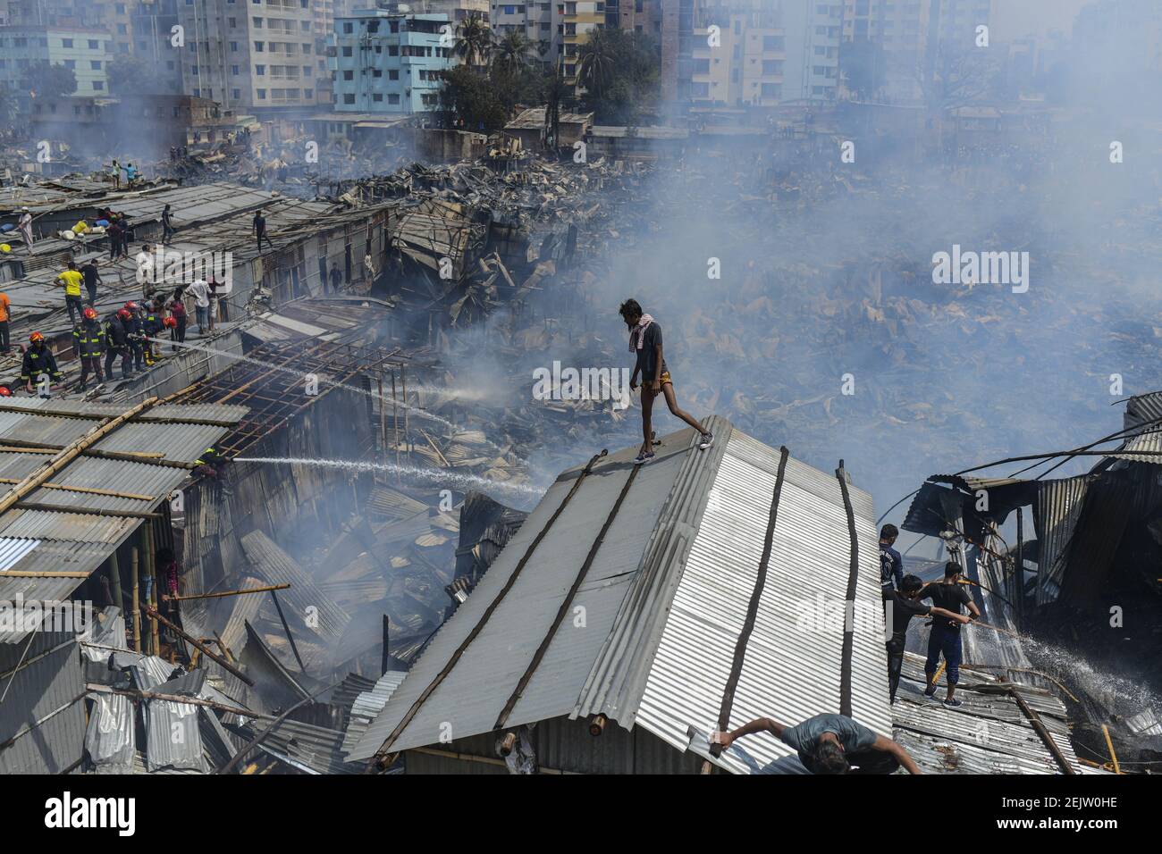 Smoke billows as firefighters work to extinguish a fire at a slum area ...