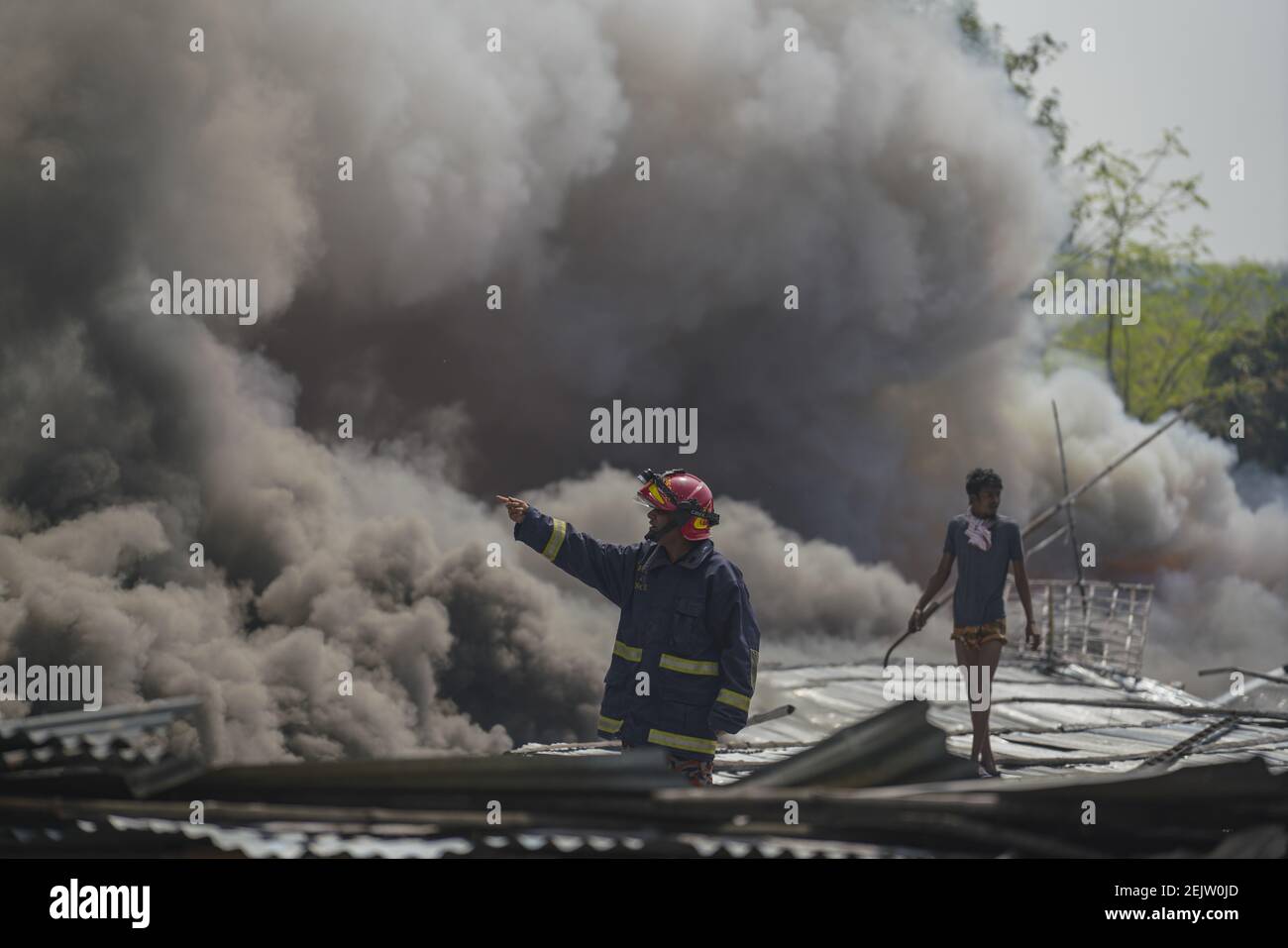 Firefighters and local people work to extinguish a fire at a slum area ...