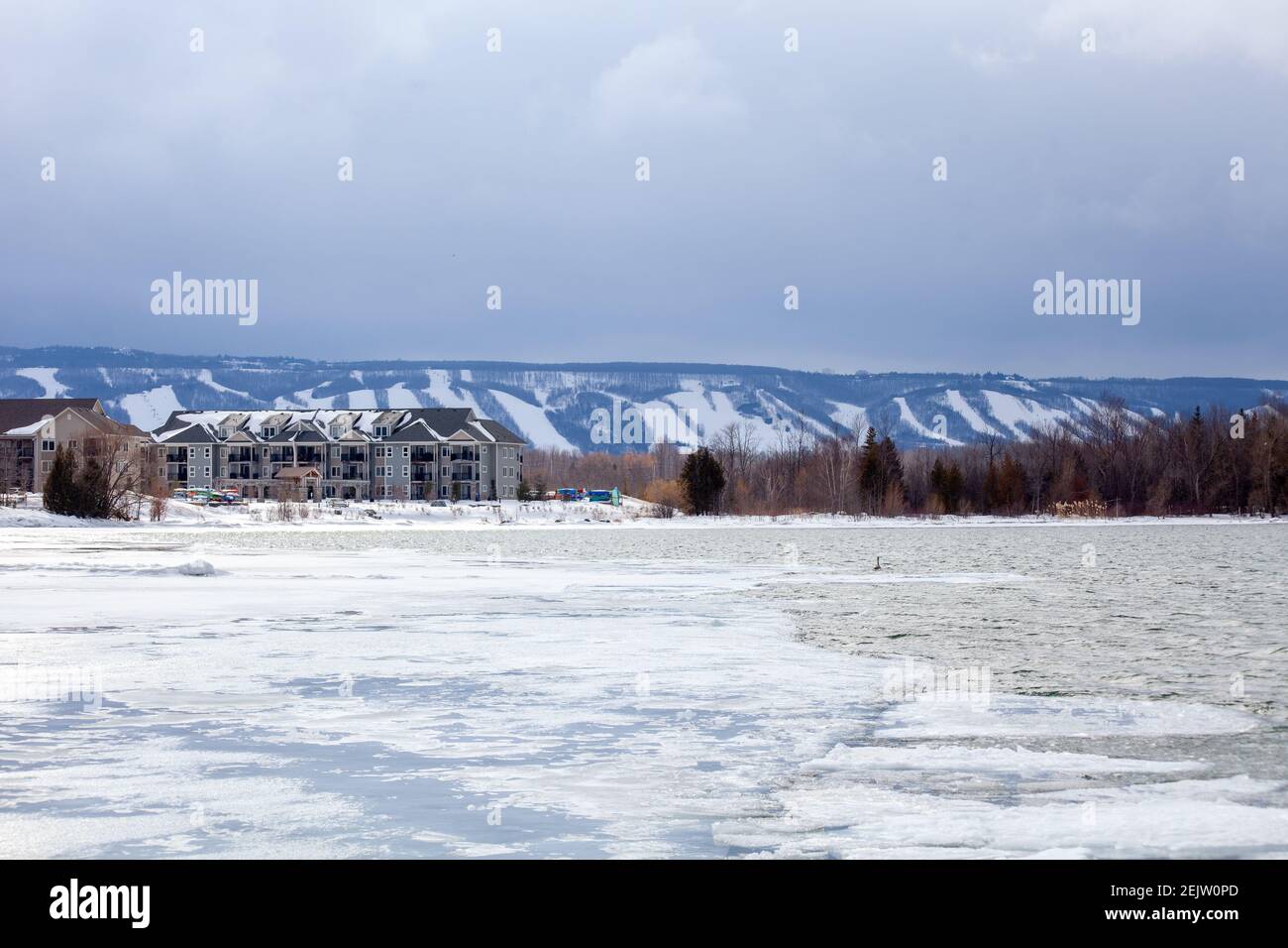 Lighthouse point condominiums look over Blue Mountain Ski hills from a distance, with the frozen Georgian Bay water beside it in the winter Stock Photo