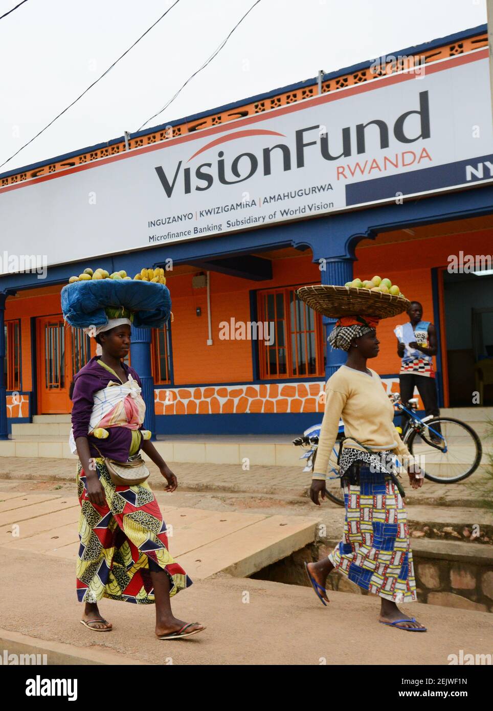 Rwandan women carrying fruits on their head outside a rural microfinancing bank. Stock Photo