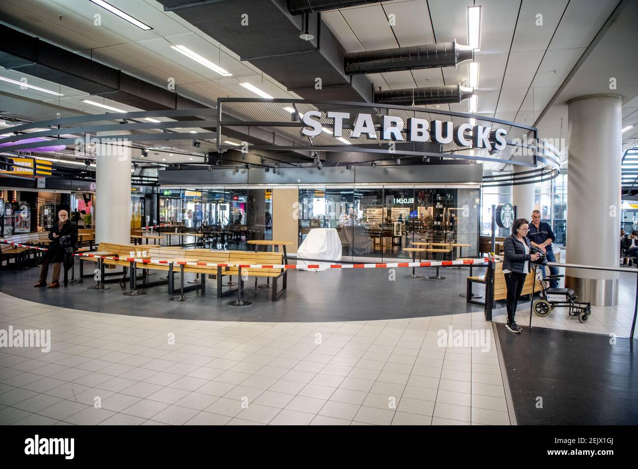 Travelers with surgical masks stand in a quieterthanusual hall at