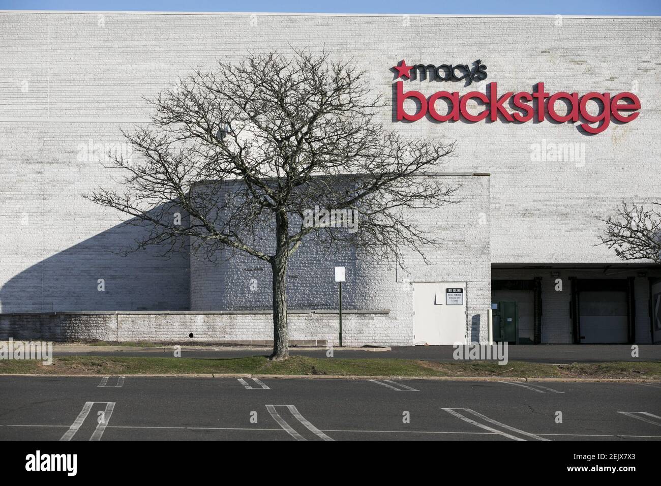 A logo sign outside of a Macy's Backstage retail store location in