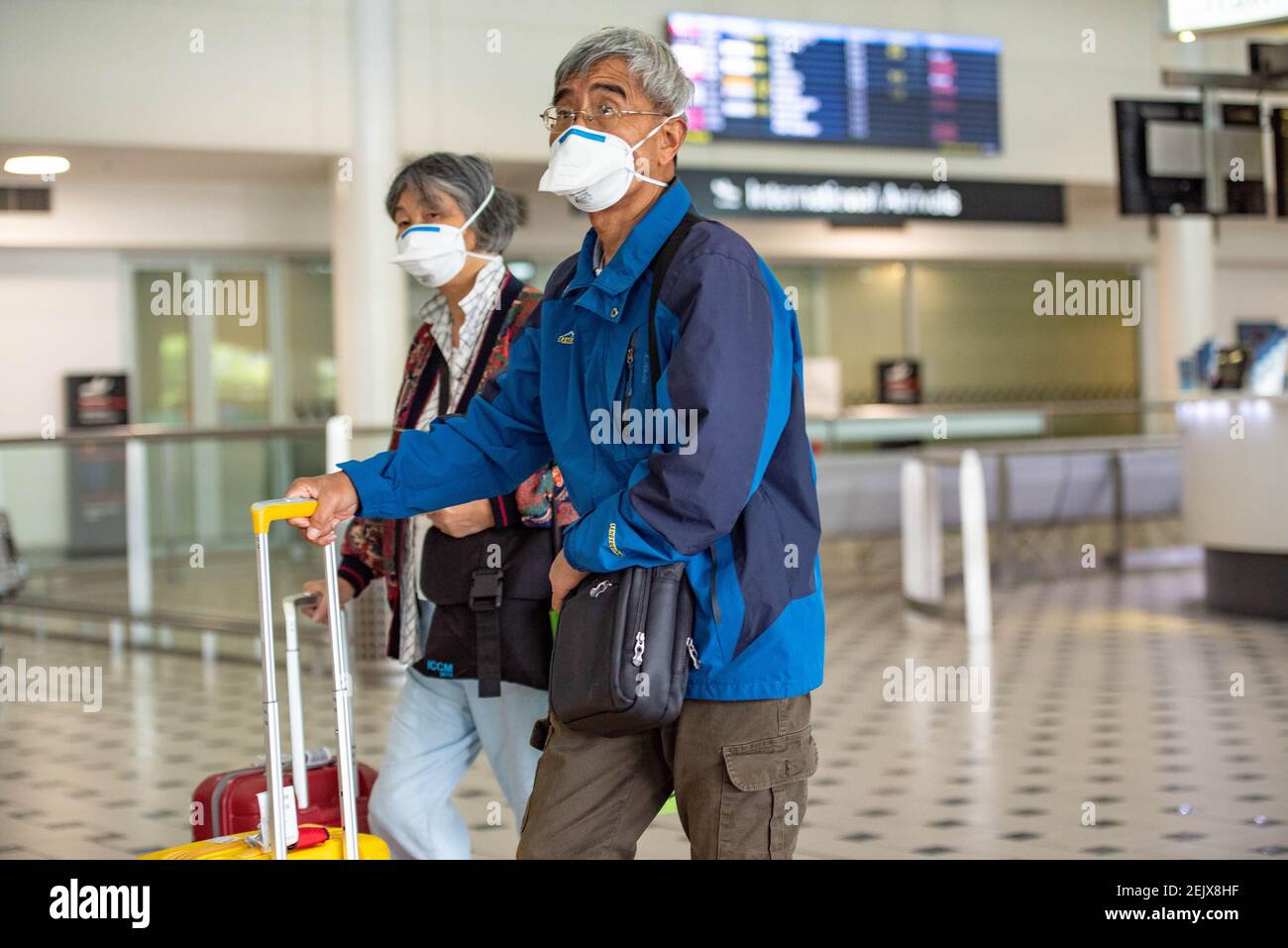 A couple wear face masks as a precaution against the spread of Coronavirus at Brisbane Airport