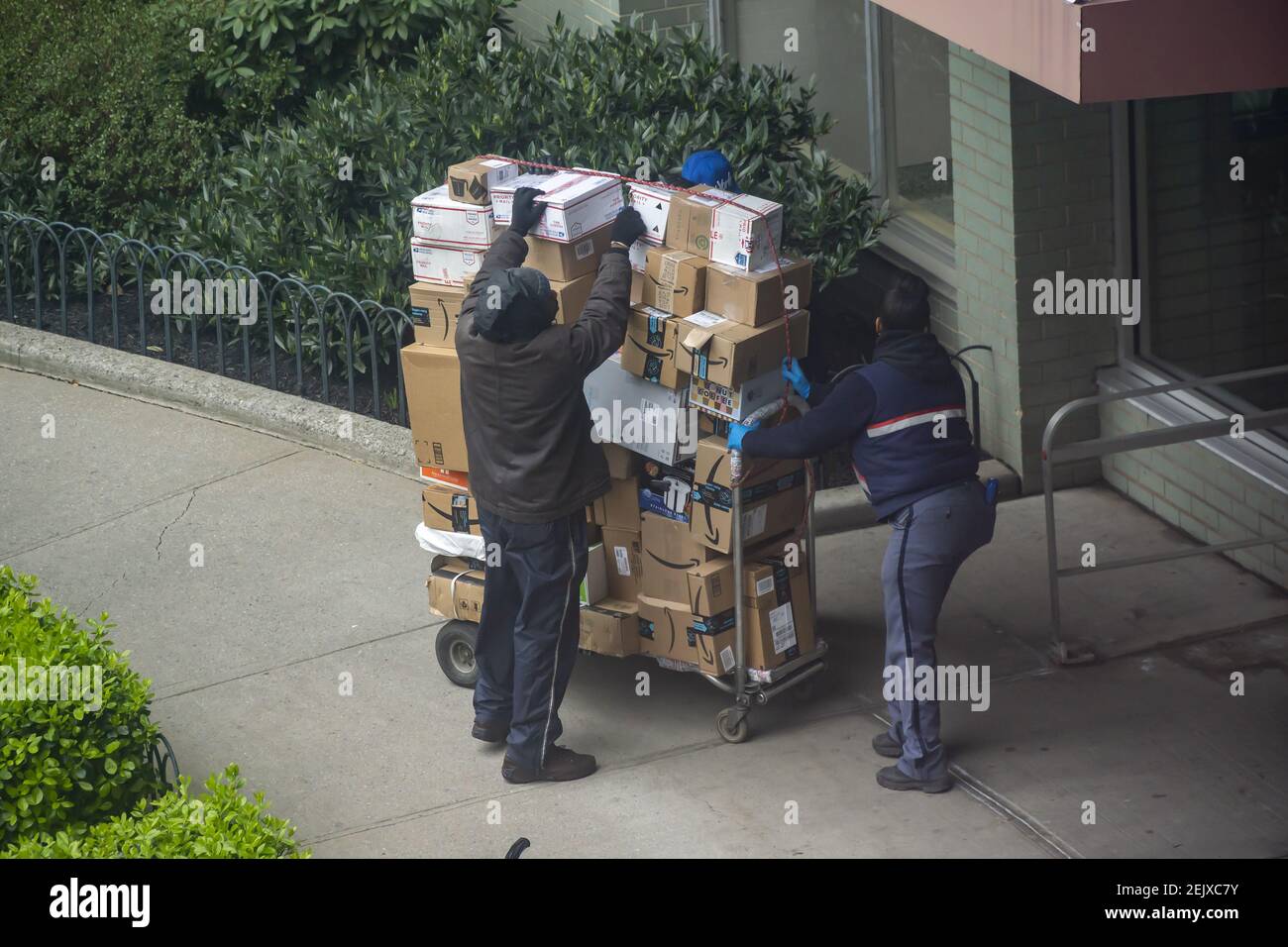 USPS workers deliver packages to an apartment building in the Chelsea neighborhood of New York
