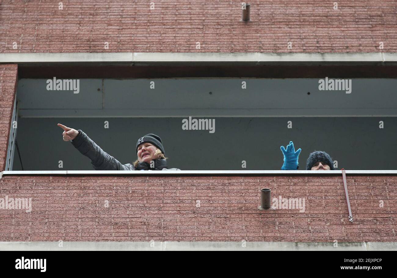 Katie Hession, left, and her mother, Joan, wave to neighbors from her father's balcony in the 2000 block of South Calumet Avenue, March 28, 2020, in Chicago. Bill Hession, 83, is in hospice care, and neighbors with their dogs gathered at his family's request to say hello and wave from a distance. (John J. Kim/Chicago Tribune/TNS) Stock Photo