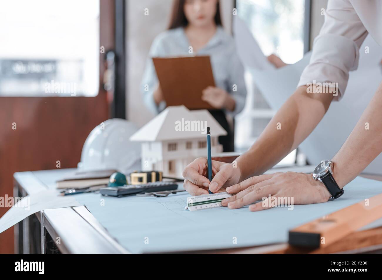 engineers holding a pen pointing to a building and drawing outlay