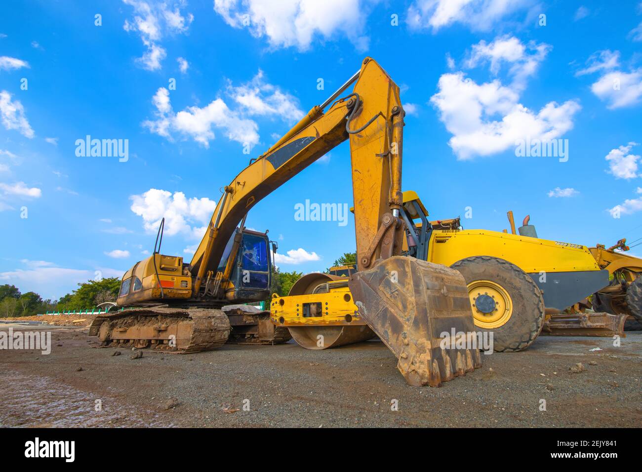 Backhoe, grader and road roller on the ground at site construction
