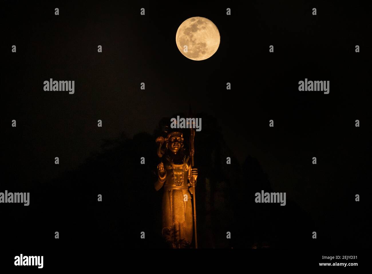 The full moon glows pink above the world's tallest Shiva temple and