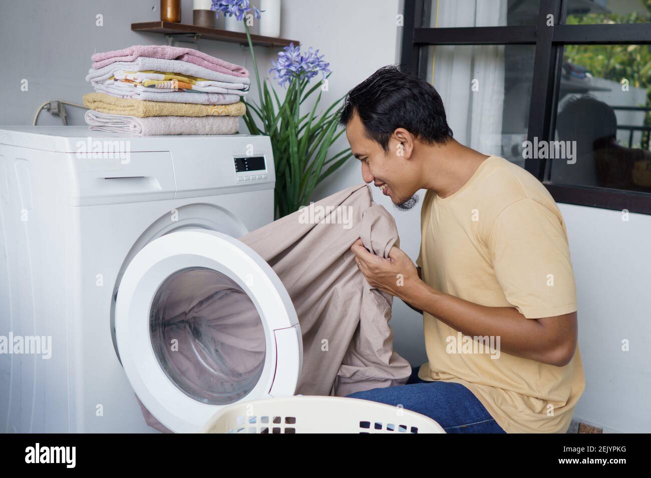 Housework. asian Man doing laundry at home loading clothes into washing