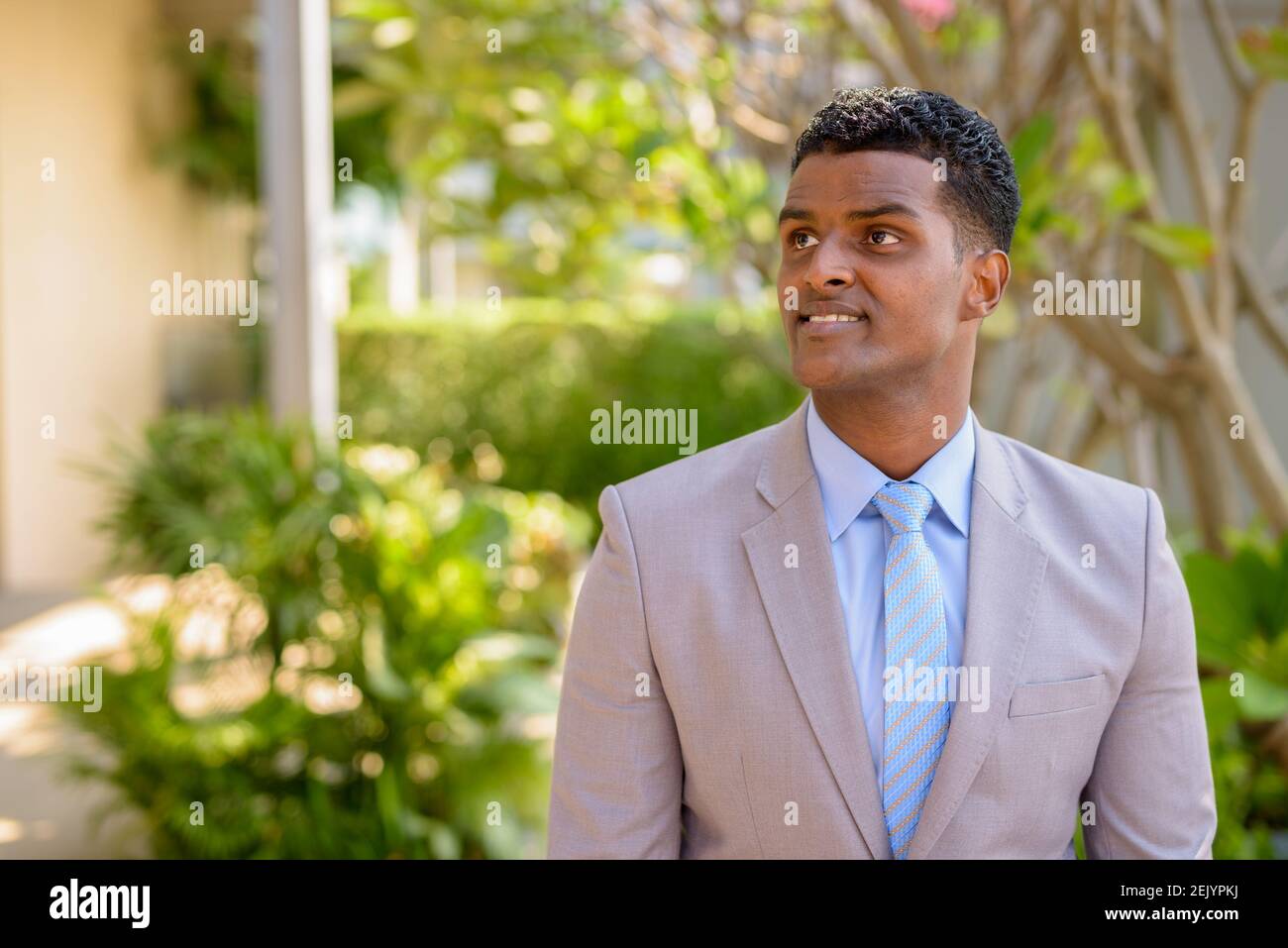 Portrait of handsome young African businessman wearing suit while ...