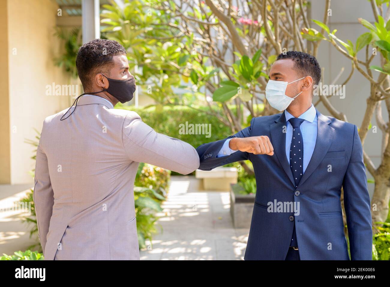 Two African businessman wearing medical mask while greeting with elbow bump greeting. Social distance concept during the coronavirus epidemic. Stock Photo