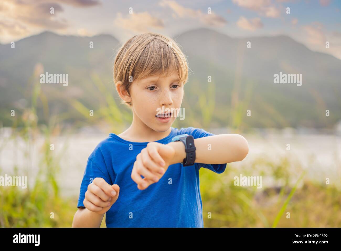 Boy uses kids smart watch outdoor against the background of the garden Stock Photo