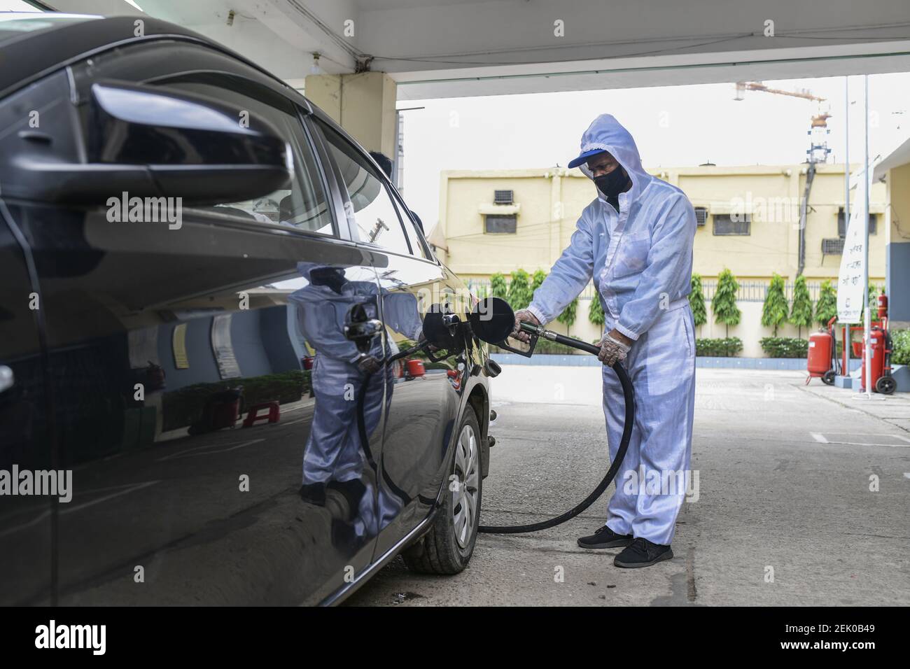 An employee wearing a personal protective equipment (PPE) fills up a ...