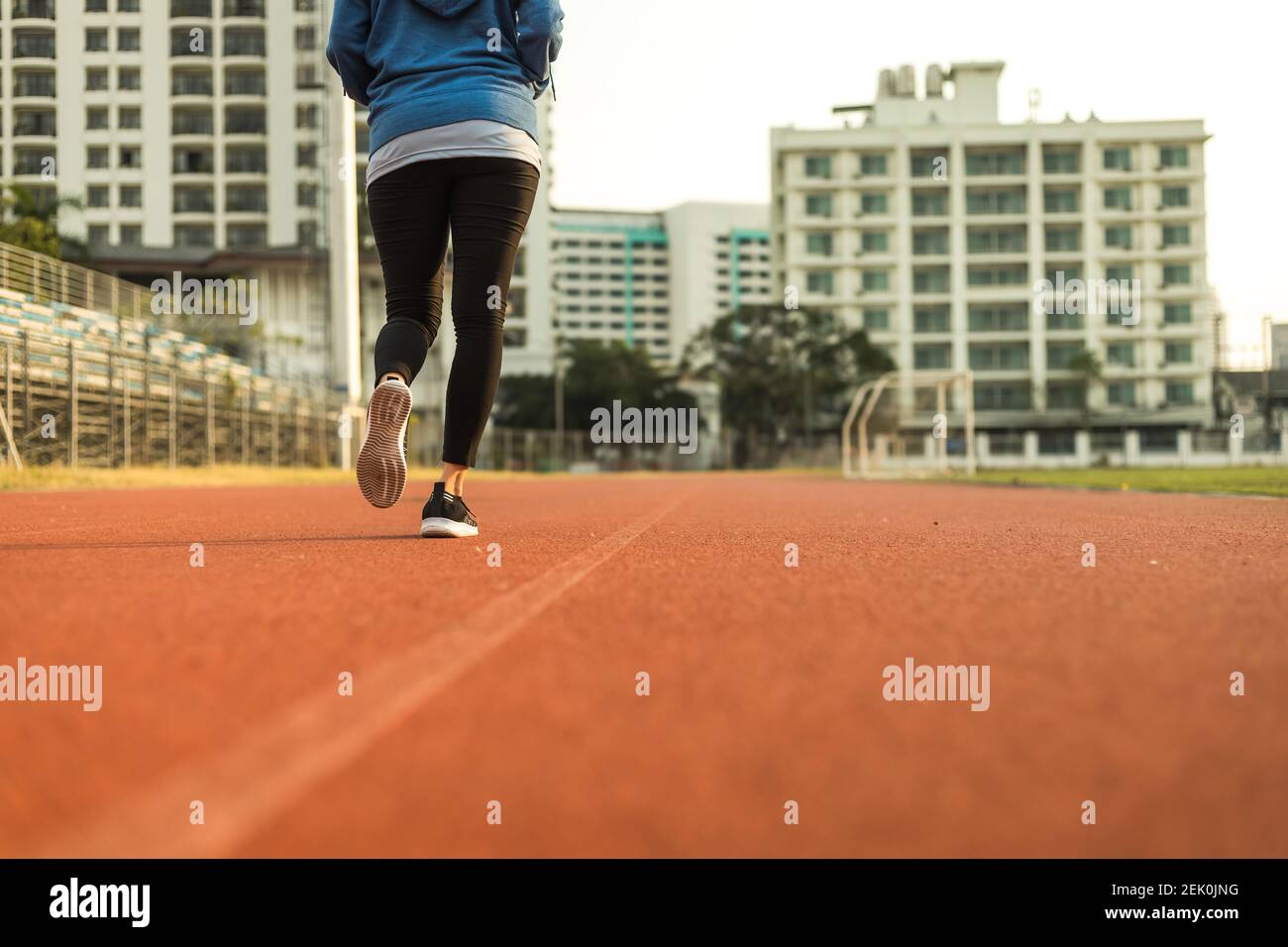 Young woman running on track race at sport stadium in the city. Stock Photo