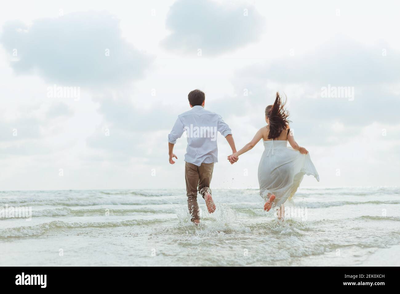 Love young couple holding hands and running on the beach. Holiday and ...