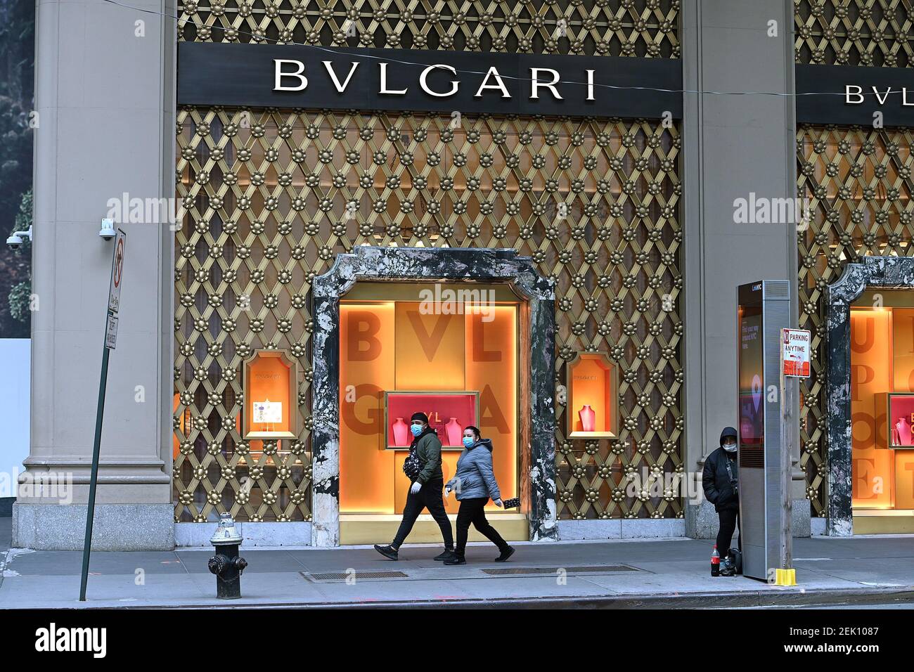 People in protective face masks walk past the luxury brand Bulgari flagship  store on 5th Ave. wich remains closed due to the COVID-19 pandemic in New  York, NY, April 27, 2020. (Anthony