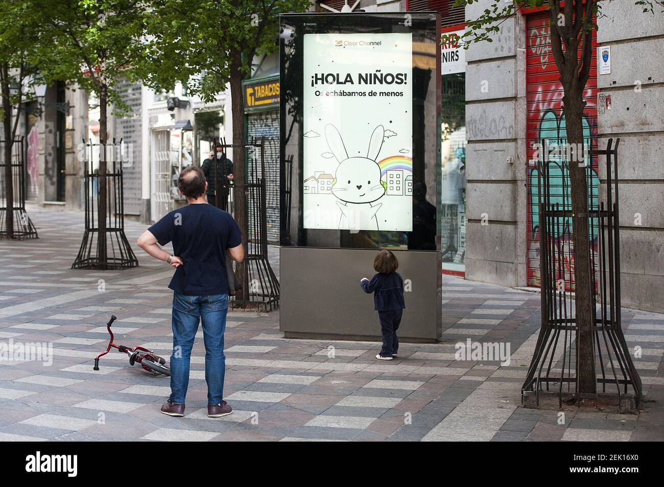 A kid observes a Clear Chanel poster with the slogan 'Hello Children. We  missed you ' during the health crisis due to the Covid-19 pandemic on April  29, 2020 in Madrid, Spain. (