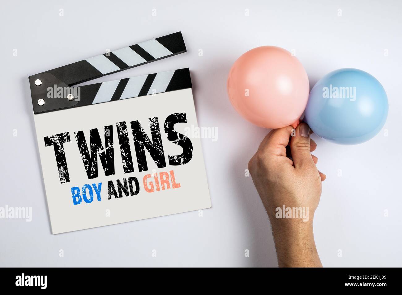 Twins, Boy and Girl. Birthday and sonographic examination concept. Movie clapper, pink and blue balloon on a white background. Stock Photo