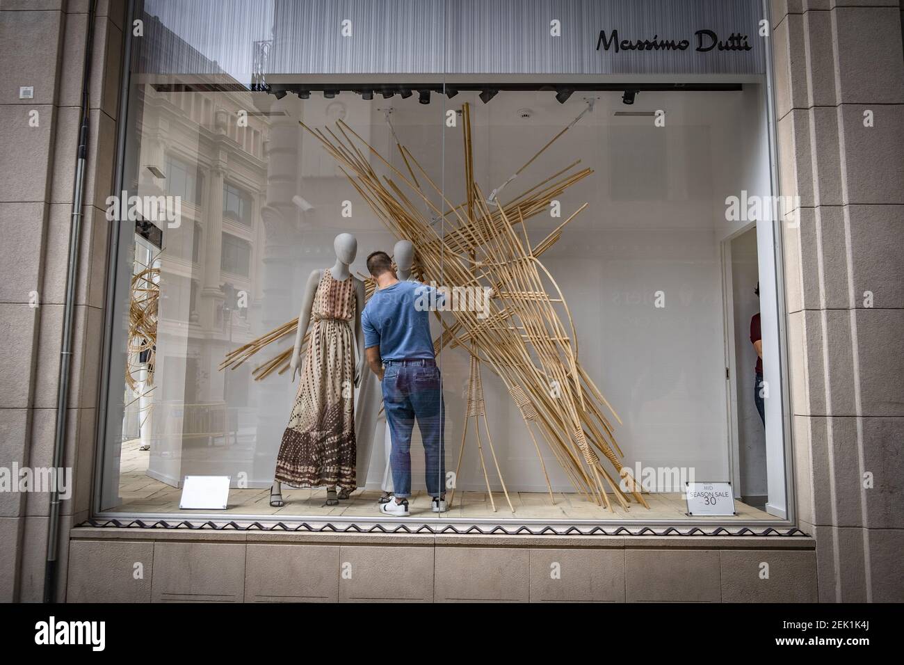 A shop assistant from the Massimo Dutti Group seen composing clothes for  the mannequins through the store window. The retail business sector is  preparing to resume business activities only with prior appointments