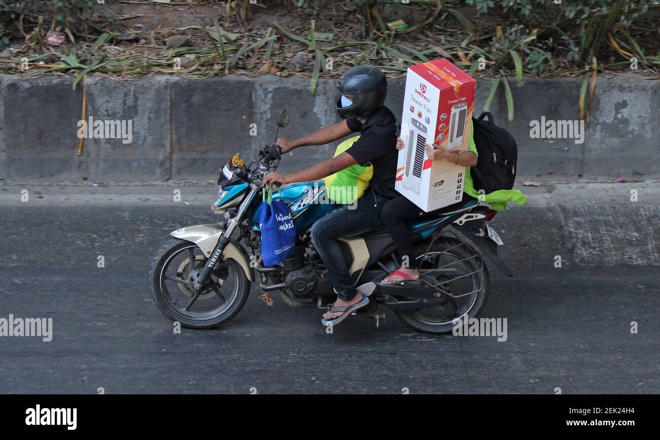 A woman rides pillion carrying air cooler during a nationwide lockdown. Day  time temperature in the city is soaring due peak summer time and high level  of humidity. Since everyone is under