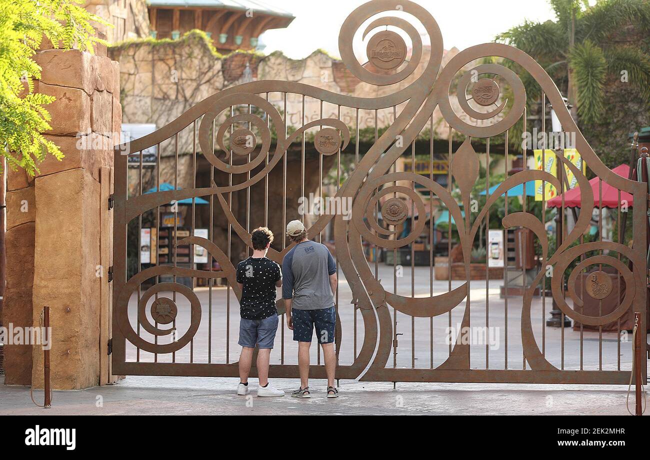 Guests peer through the closed gate to Universal's Islands of Adventure beside Universal CityWalk in Orlando, Fla., on Thursday, May 14, 2020. Universal began limited operation of select venues at CityWalk on Thursday, while also limiting capacity and increasing cleaning and disinfection procedures due to the Coronavirus pandemic. (Stephen M. Dowell/Orlando Sentinel/TNS) Stock Photo