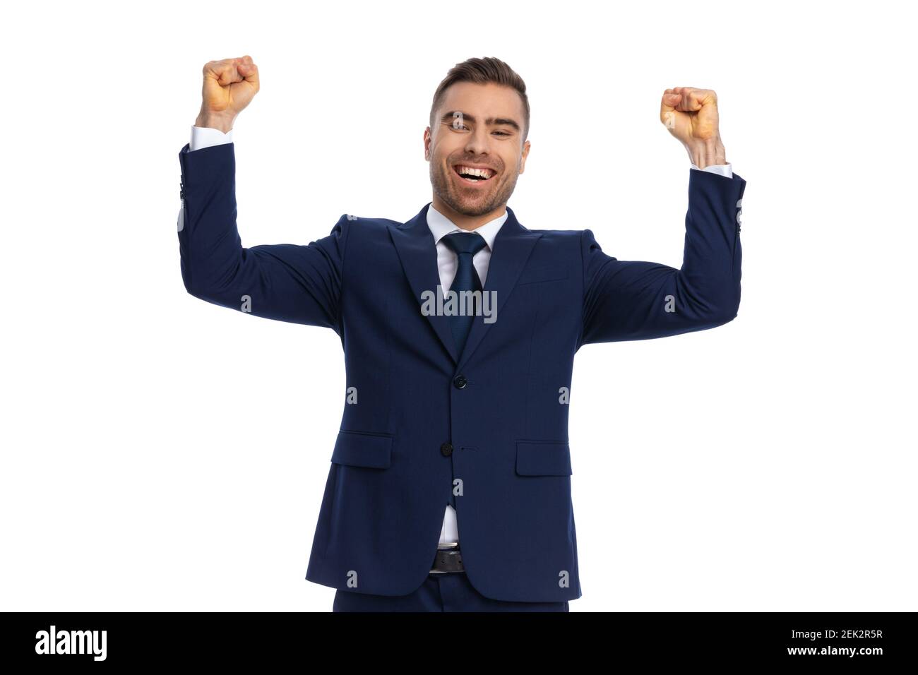 excited young businessman in navy blue suit holding fists in the air ...