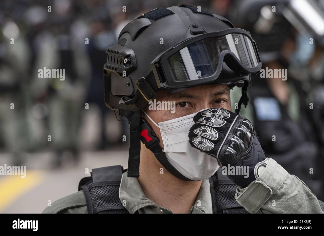 A riot police officer looks on while wearing a face mask as a ...
