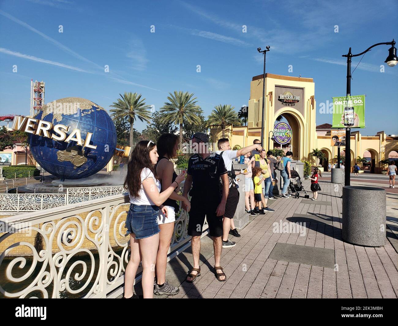 Visitors to Universal Orlando lean against the railing of the bridge ...