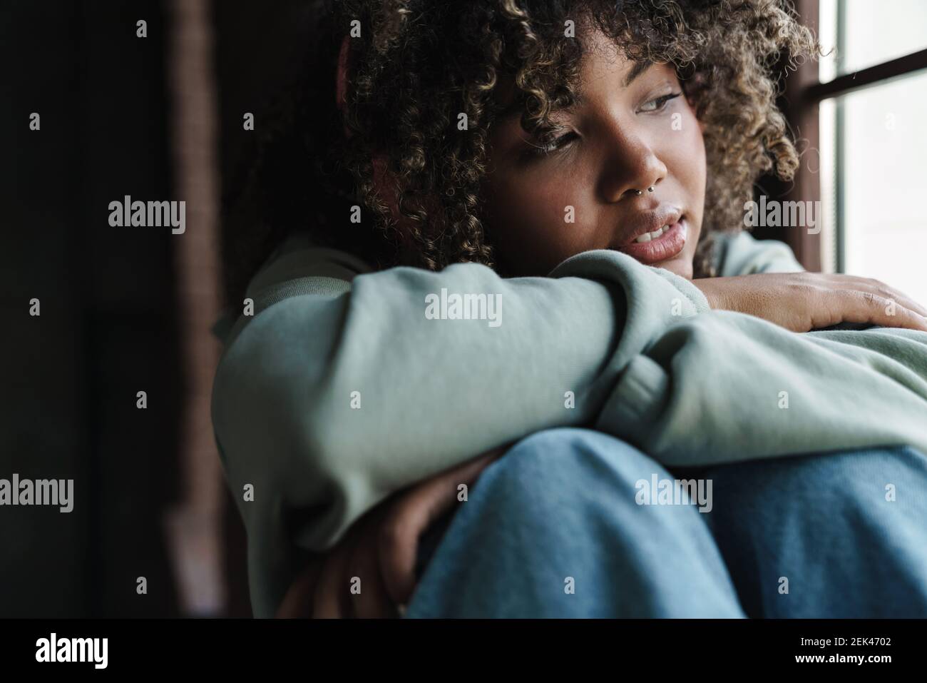 Focused african american woman looking at window while sitting on ...