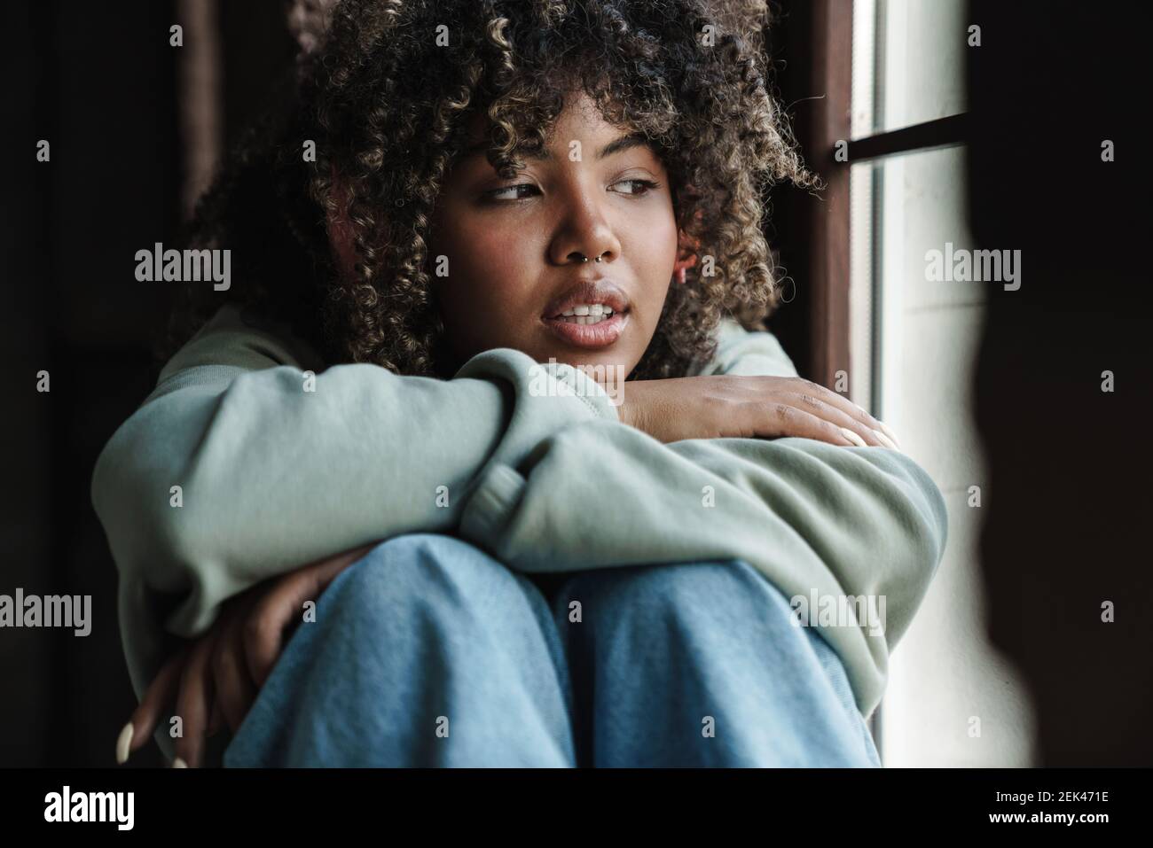 Focused african american woman looking at window while sitting on ...