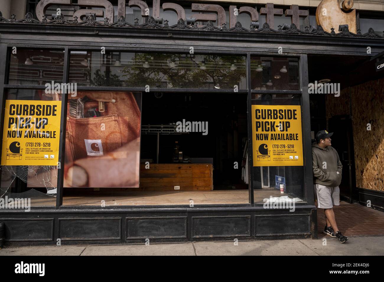 A pedestrian stands outside of the broken windows of a Carhartt store in the Wicker Park neighborhood after looting occurred during another night of protests in response to the police killing of George Floyd on Monday June 1, 2020 in Chicago, IL. (Photo by Christopher Dilts / SIPA USA ) Stock Photo
