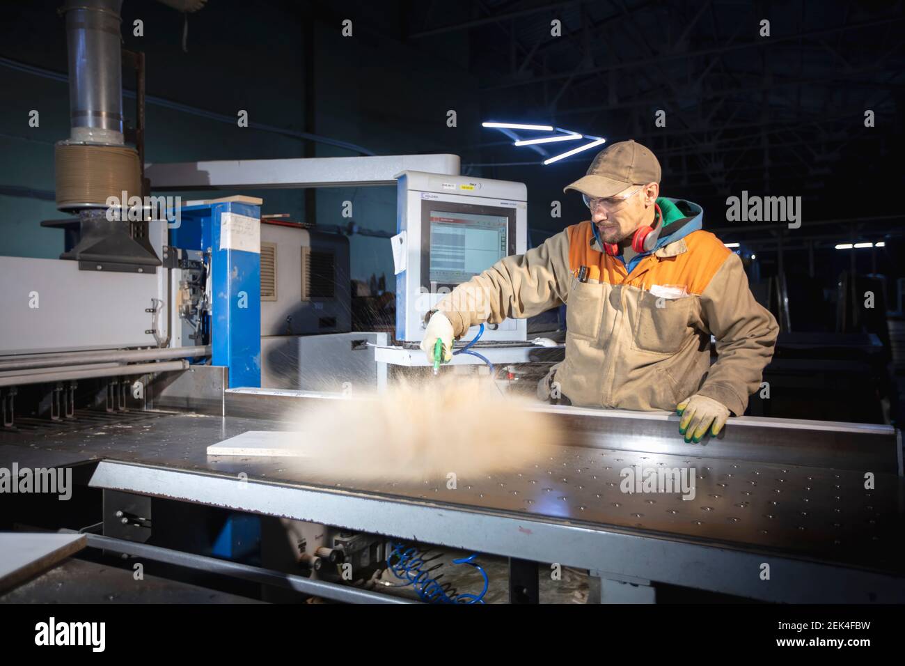 A furniture manufacturing worker at a cutting machine makes furniture