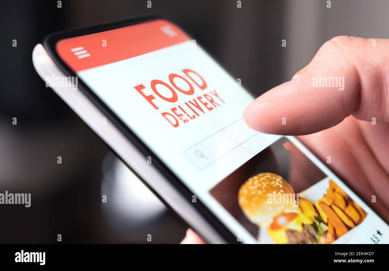 Restaurant food delivery service in phone. Take away menu in digital mobile app. Man ordering takeout pizza or burger online. Fast lunch delivered. Stock Photo