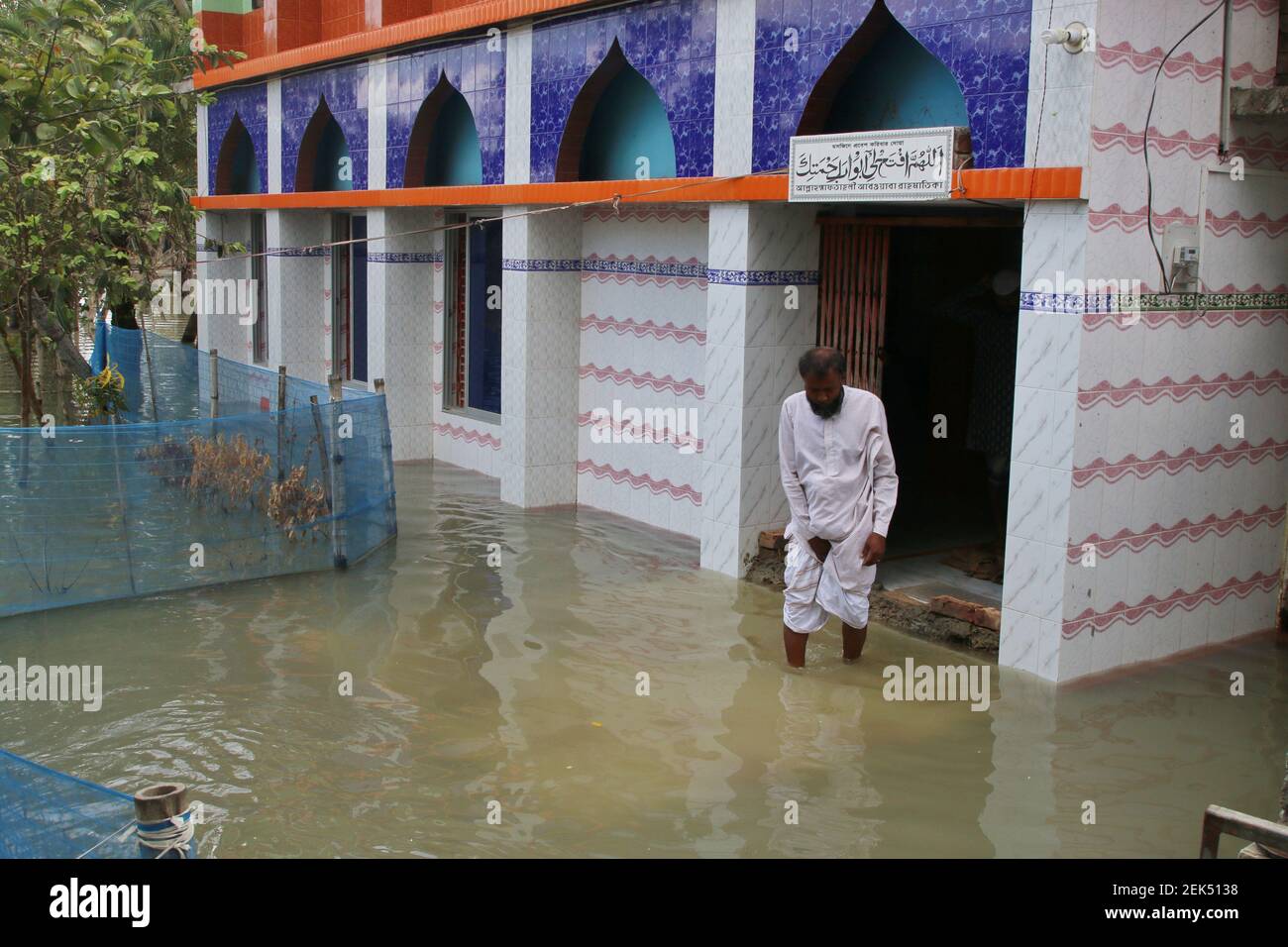 A Muslim man leaves a flooding Mosque as the embankment of the coastal
