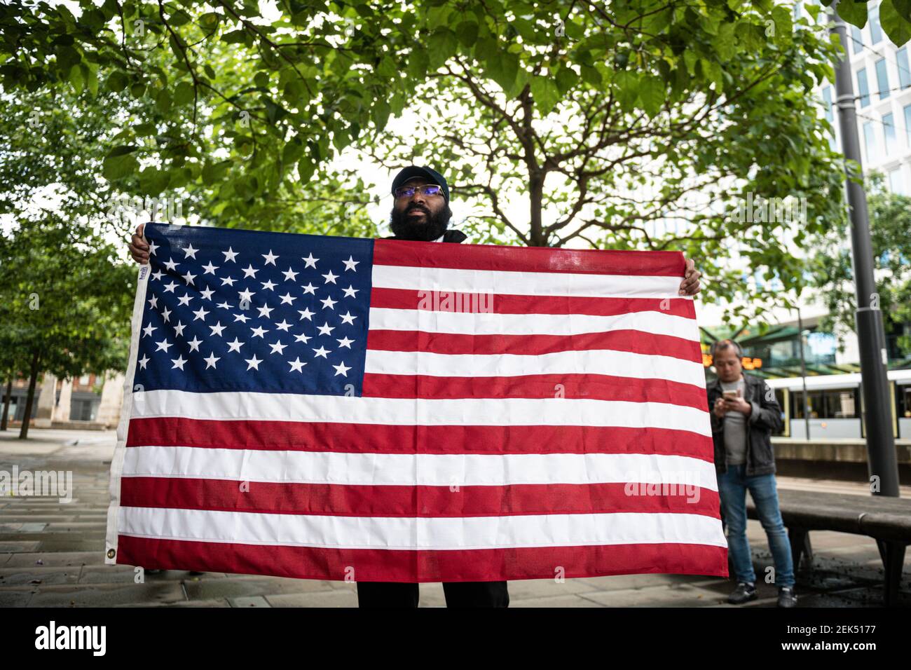 A protester holds a US flag during the demonstration. Hundreds of people together with the members of the Fire & Rescue service took to the streets in solidarity with the Black Lives Matter march following the killing of George Floyd, a black man who died in police custody in Minneapolis. (Photo by Kenny Brown / SOPA Images/Sipa USA)  Stock Photo