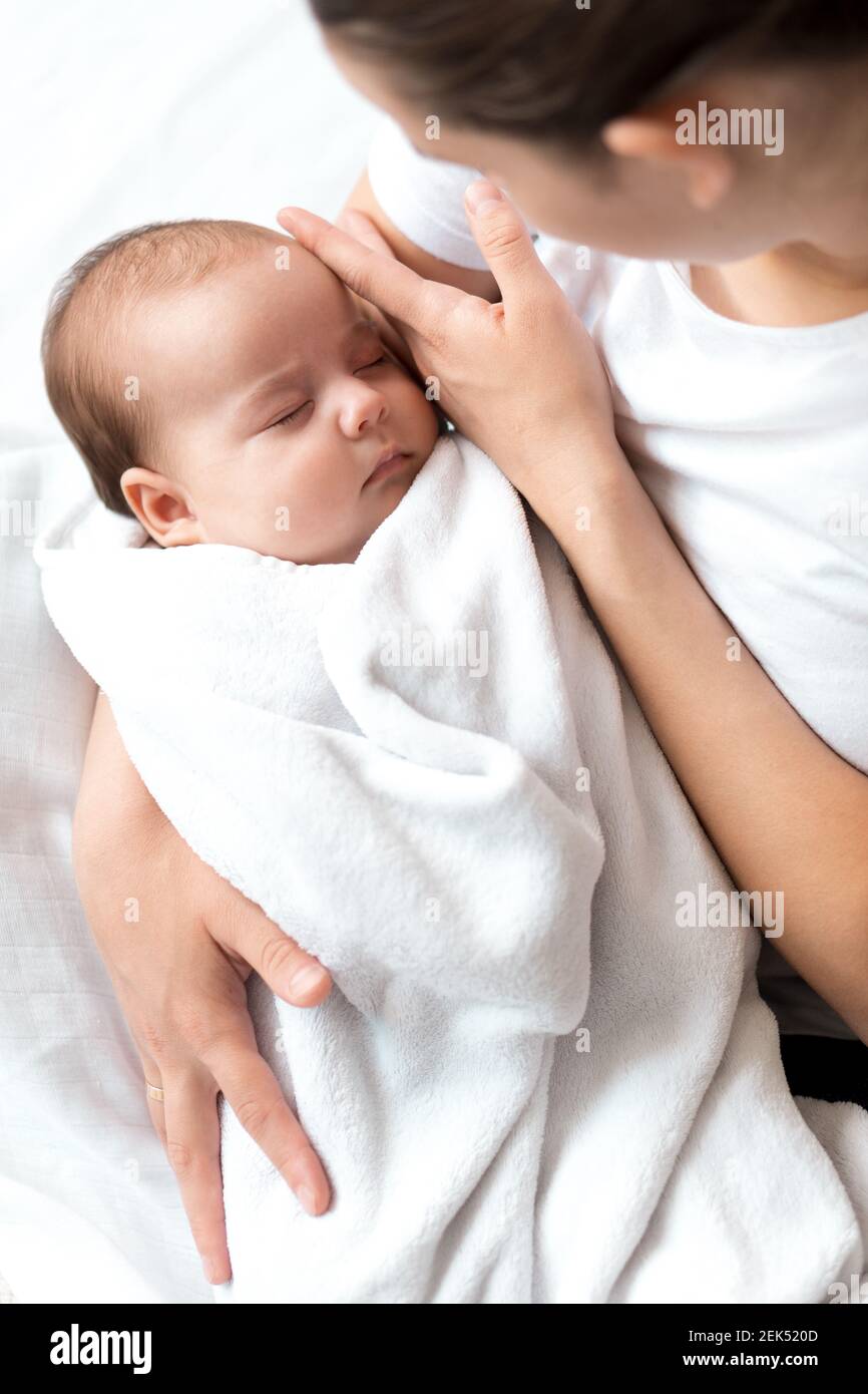 close-up portrait of mom with newborn baby on white background copy space. Young cute caucasian woman black haired holding child in arms motherhood Stock Photo