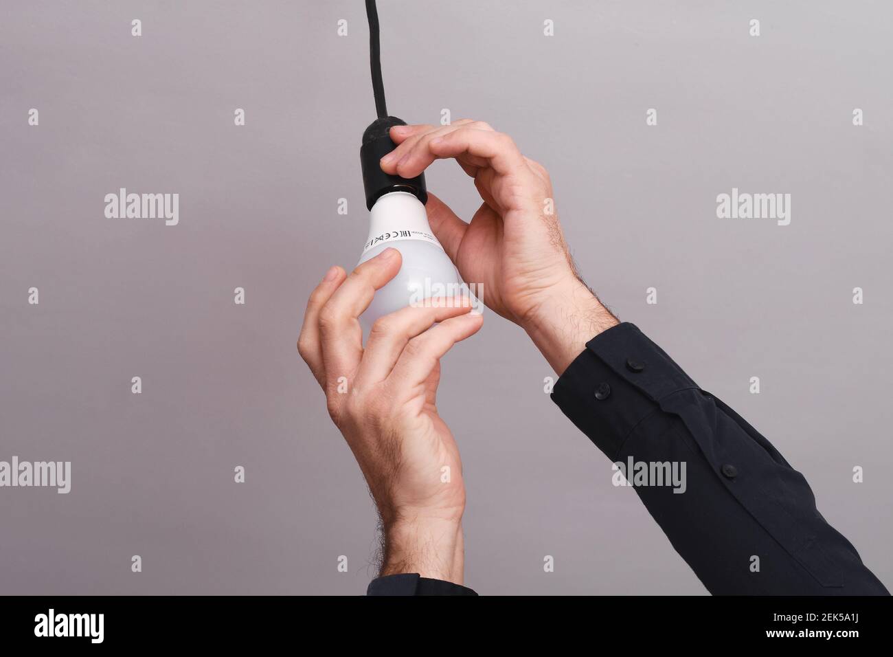 Male hands screw an LED light bulb in holder  Stock Photo
