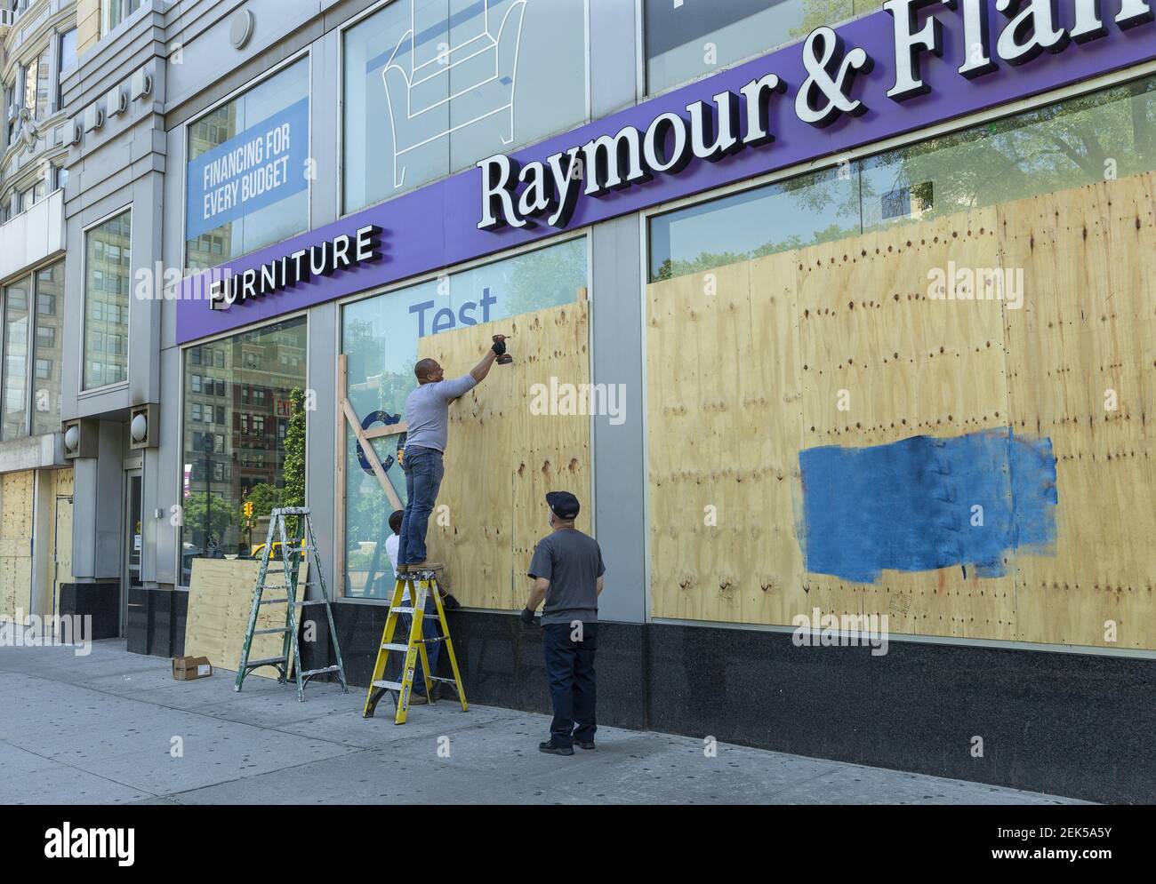 Workers dismantle plywood from windows of Raymour & Flanigan furniture