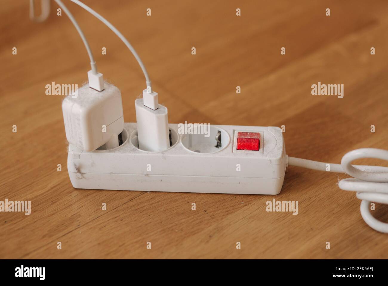 Dusty white extension cord at home. Dangerous inflammation Stock Photo