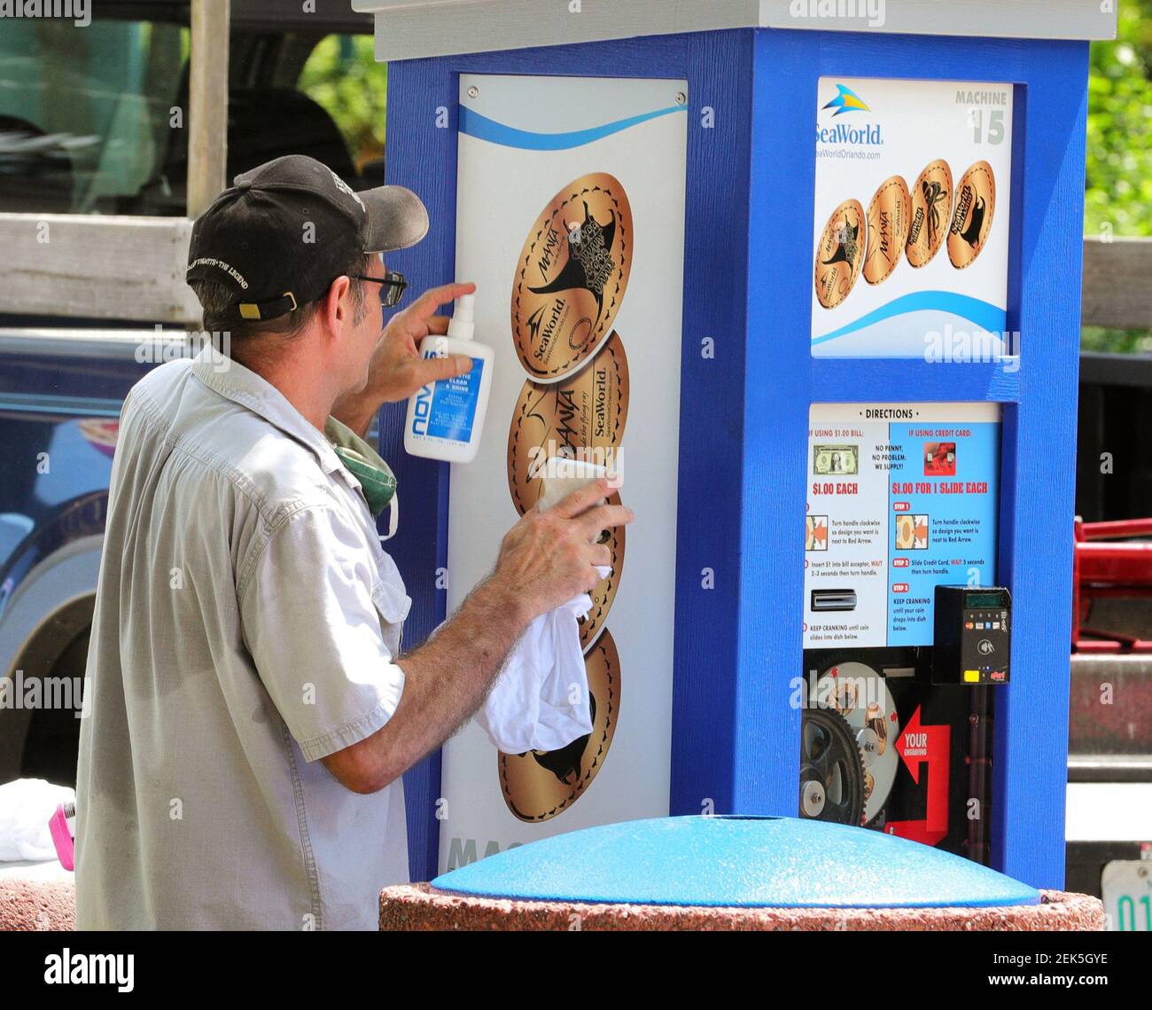 At Sea World Orlando, an emloyee sanitizes a souvenir coin kiosk on Wednesday, June 10, 2020, ahead of the park's formal reopening on Thursday. The Orlando, Fla., park has been closed since March 16 due to the coronavirus pandemic. (Joe Burbank/Orlando Sentinel/TNS) Stock Photo