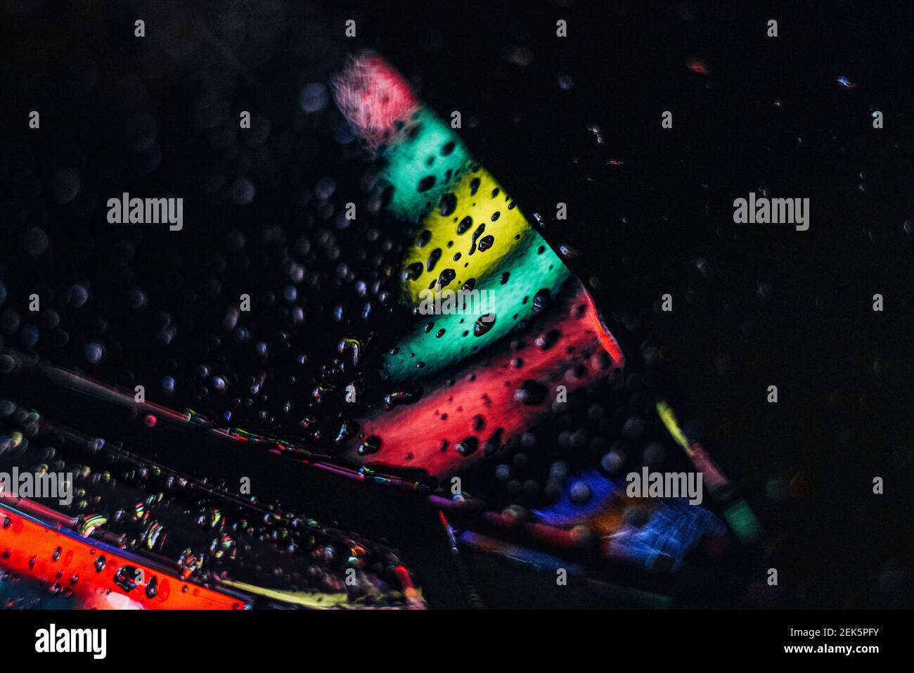Kšln, 18.02.21: Strassen von Kšln leuchten in bunten Farben nach einem abendlichen Regen; Wassertropfen sammeln sich auf einem Auto und werden farblic Stock Photo